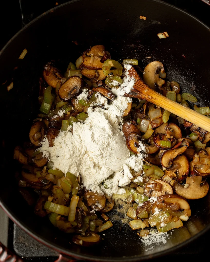 Add flour to mushrooms
