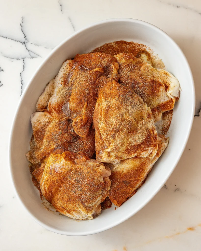 Add spices to chicken thighs